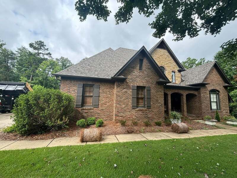 A large brick house with hay bales in front of it