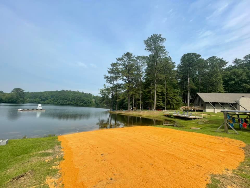 A dirt road leading to a lake with a boat in the water.