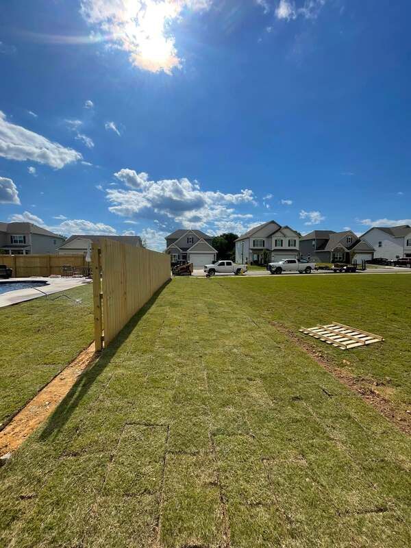 There is a wooden fence in the middle of a lush green field.