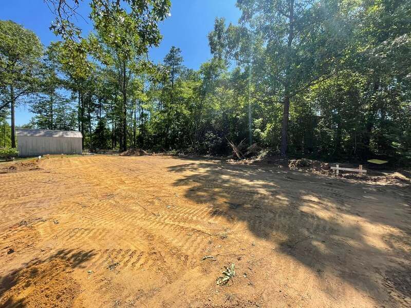 A large dirt field with trees in the background.