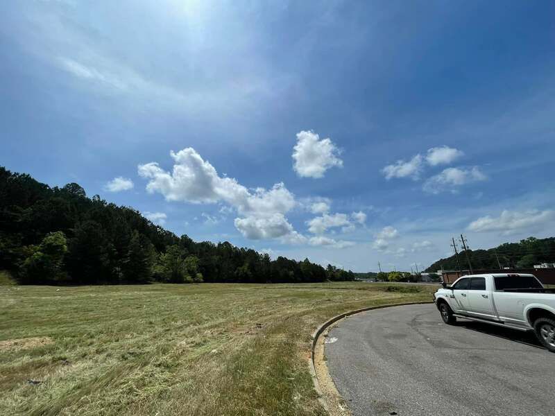 A white truck is parked in a parking lot next to a field.