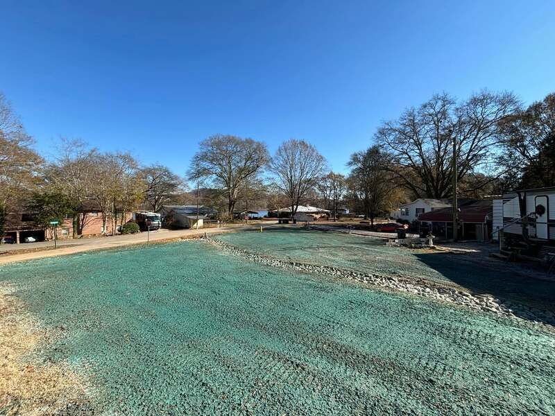 A large green field with trees in the background and a blue sky in the background.