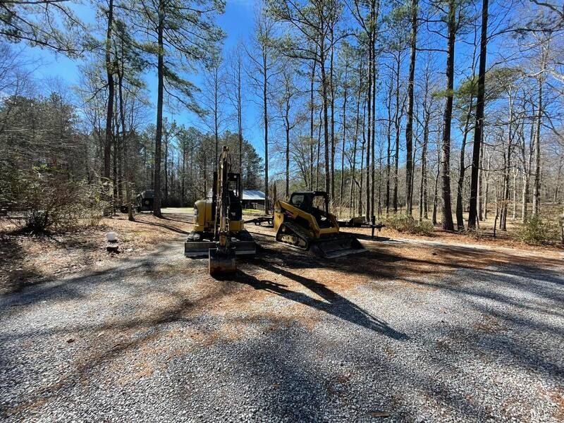 A couple of tractors are parked on the side of a gravel road.