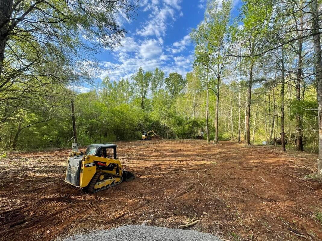A bulldozer is sitting in the middle of a forest.