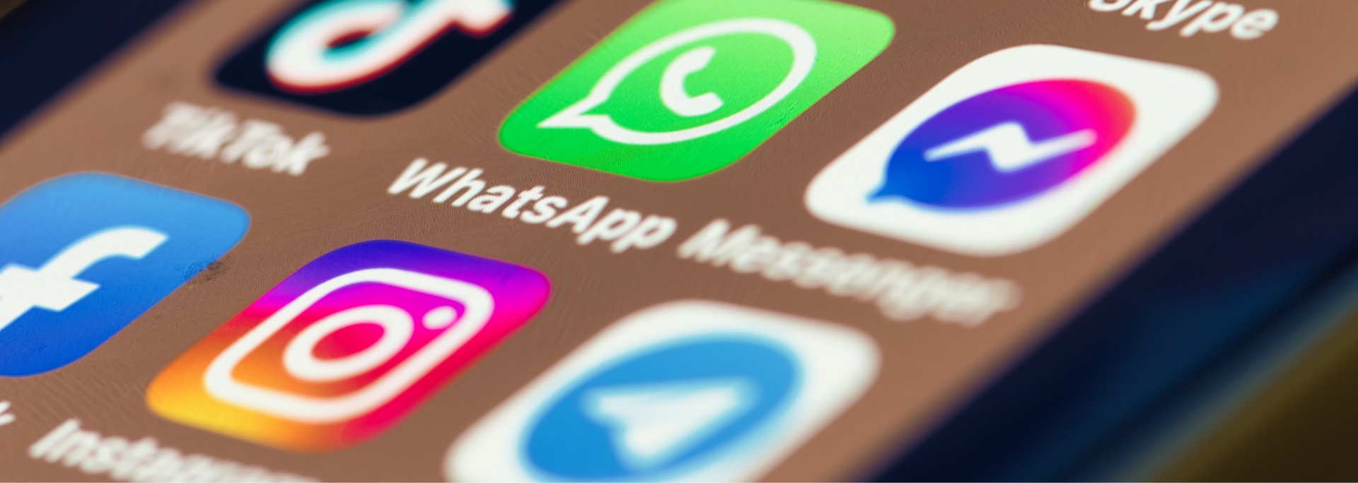 Close-up of smartphone app icons for TikTok, WhatsApp, Messenger, X, Instagram, and Telegram on a tilted screen