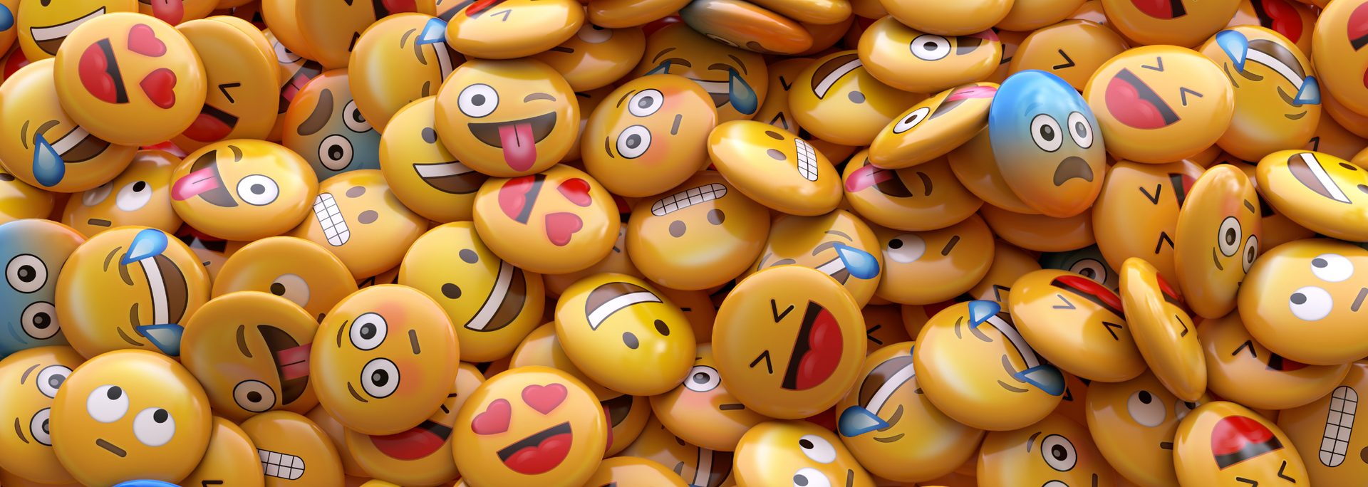 Pile of yellow emoji balls with varied facial expressions, including heart eyes, laughter, and winking faces