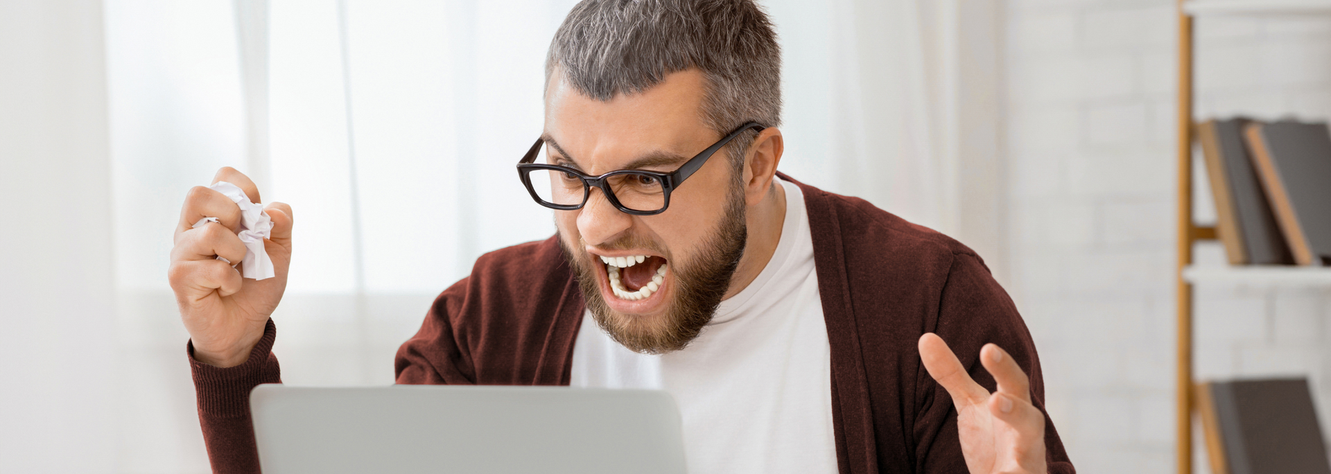 Smiling man with glasses raising his fists in excitement indoors
