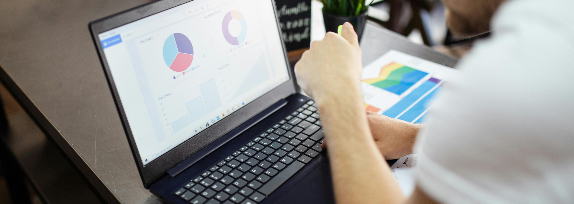 Person viewing analytics charts on a laptop beside printed reports and a color swatch sheet