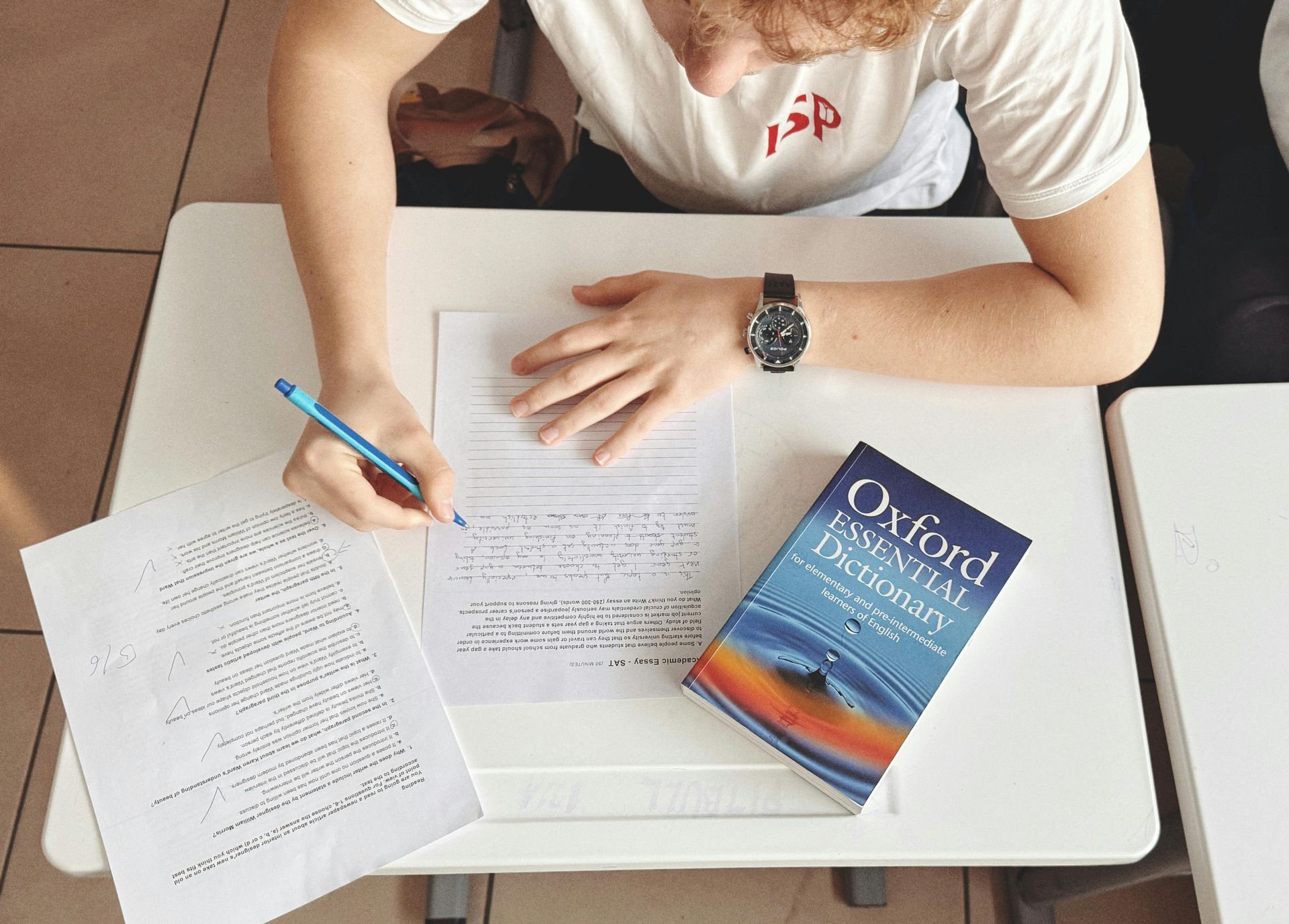 Person writing at a desk with study notes and an Oxford handbook book on the right