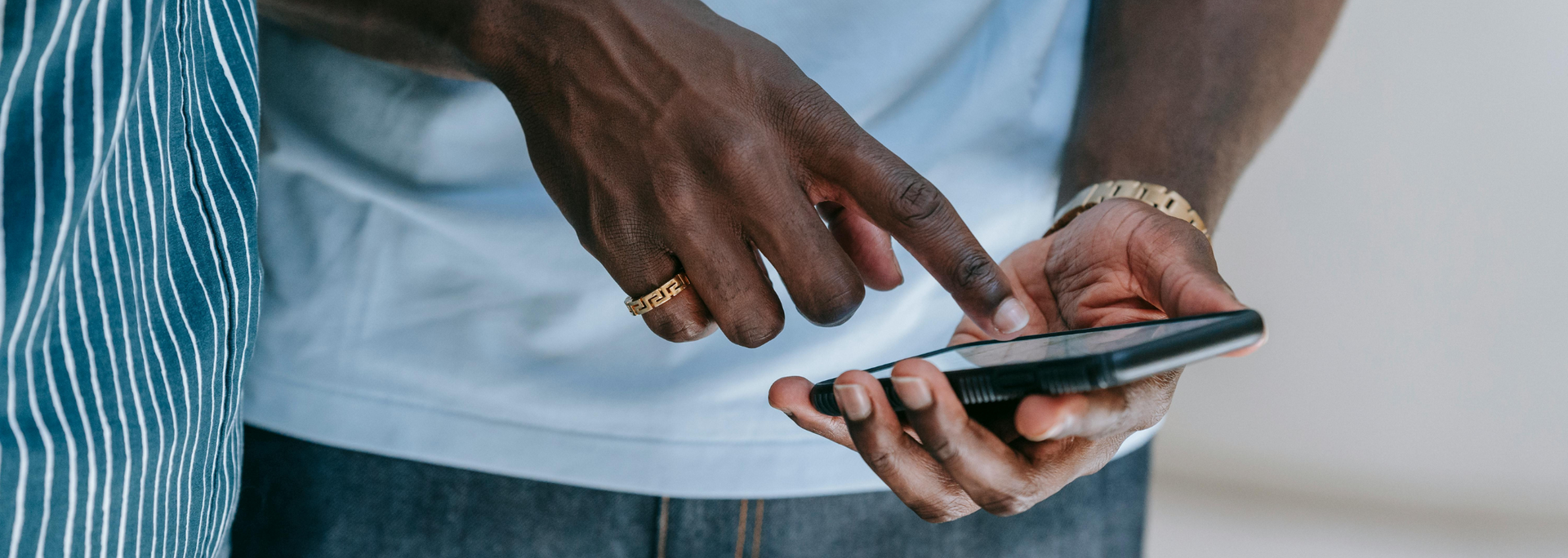 Close-up of hands using a smartphone against a blue-and-white striped background