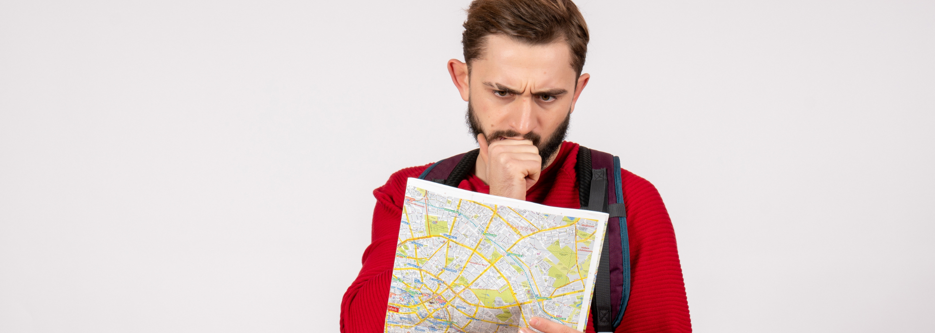 Man in red sweater holding a folded map and looking thoughtfully at it