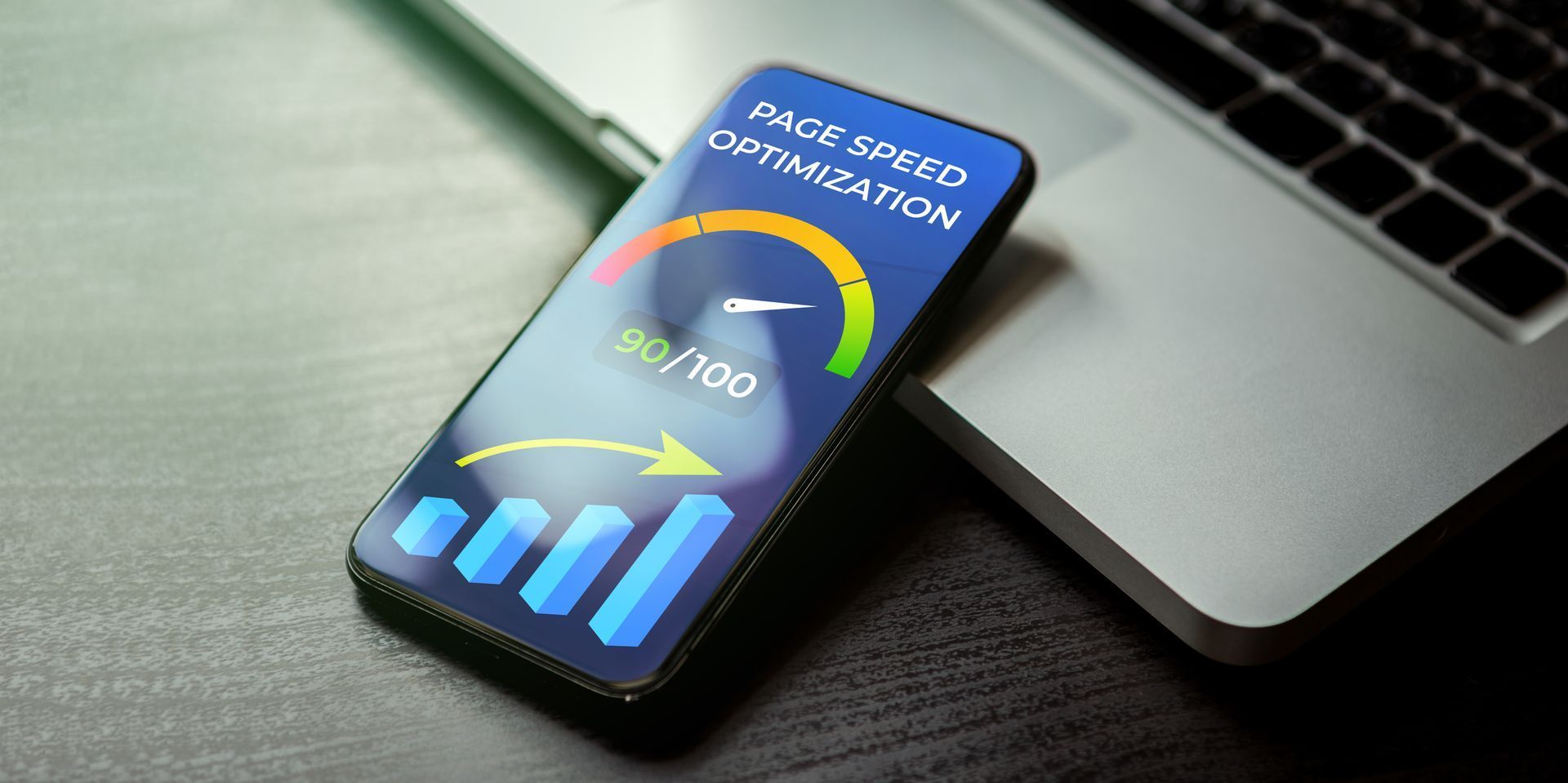 Smartphone showing a Wi‑Fi speed test with colorful bars beside a laptop keyboard