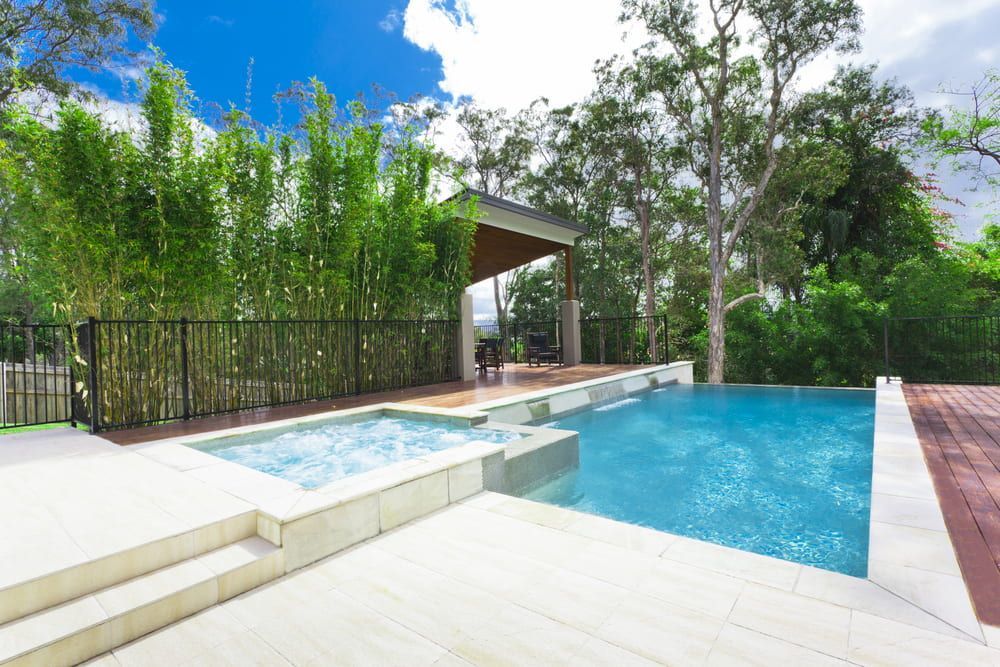 A Large Swimming Pool With A Hot Tub In The Backyard — Solitary Island Pools in Coffs Harbour, NSW