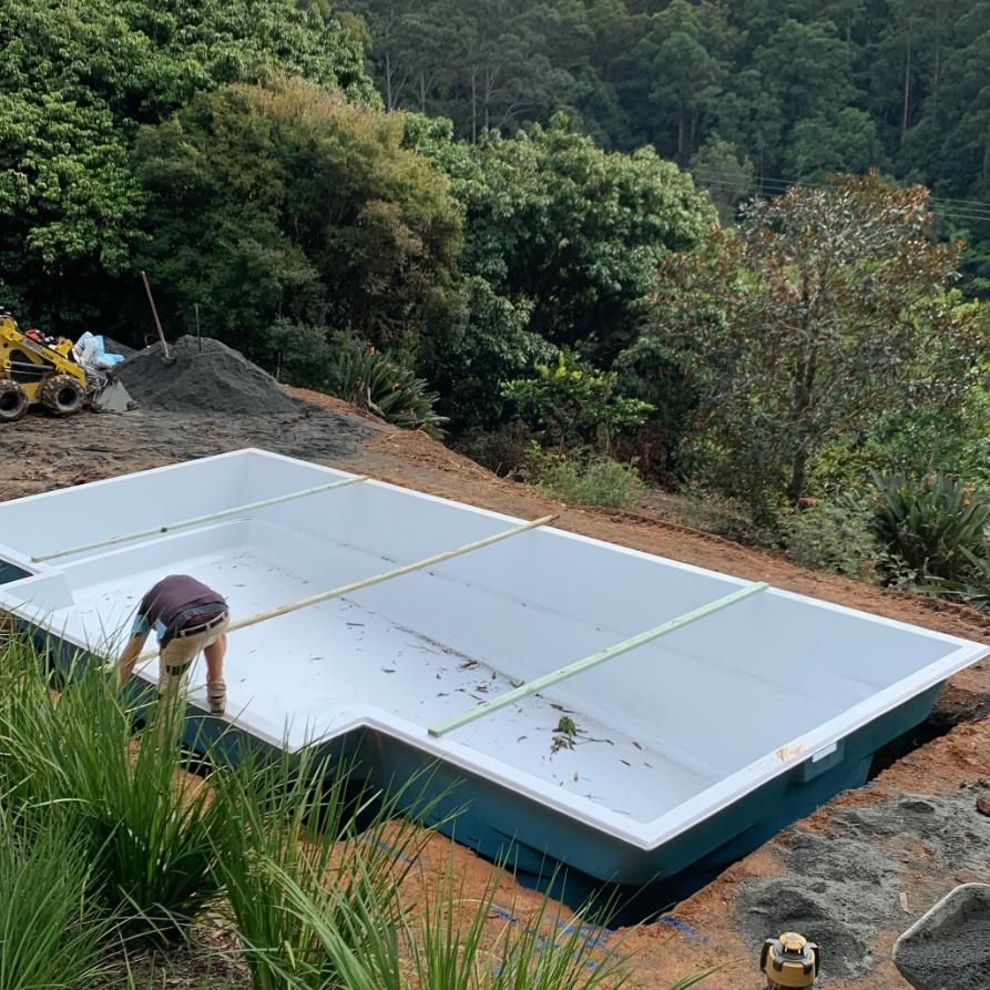 A Man Is Measuring A Large Swimming Pool In The Dirt — Solitary Island Pools In Coffs Harbour, NSW