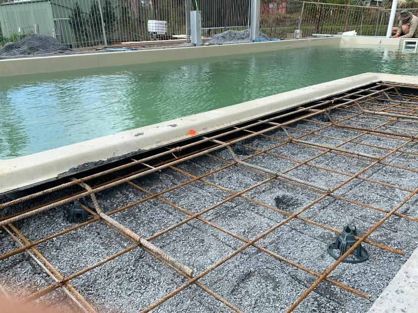 A Swimming Pool Is Being Built Next To A Concrete Floor — Solitary Island Pools In Coffs Harbour, NSW