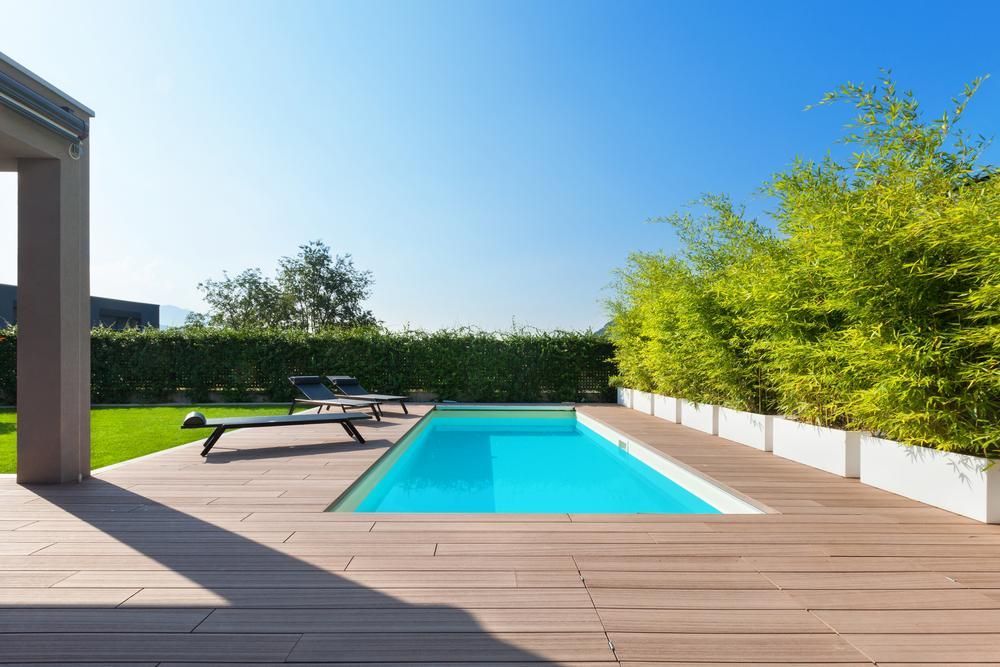 Pool Area With Wooden Deck, Pool, Lounge Chair, and Lush Greenery — Solitary Island Pools in Coffs Harbour, NSW