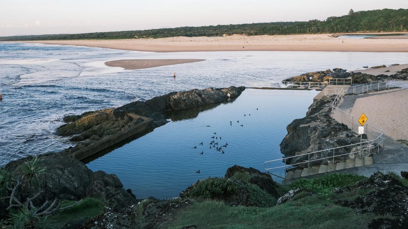 A Large Body Of Water Is Surrounded By Rocks On The Shore Of A Beach — Solitary Island Pools in Sawtell, NSW