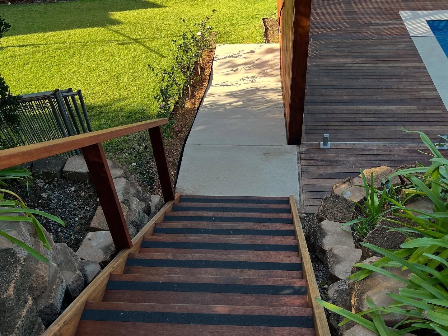 Wooden Stairs Leading Down to a Concrete Path and Pool Deck