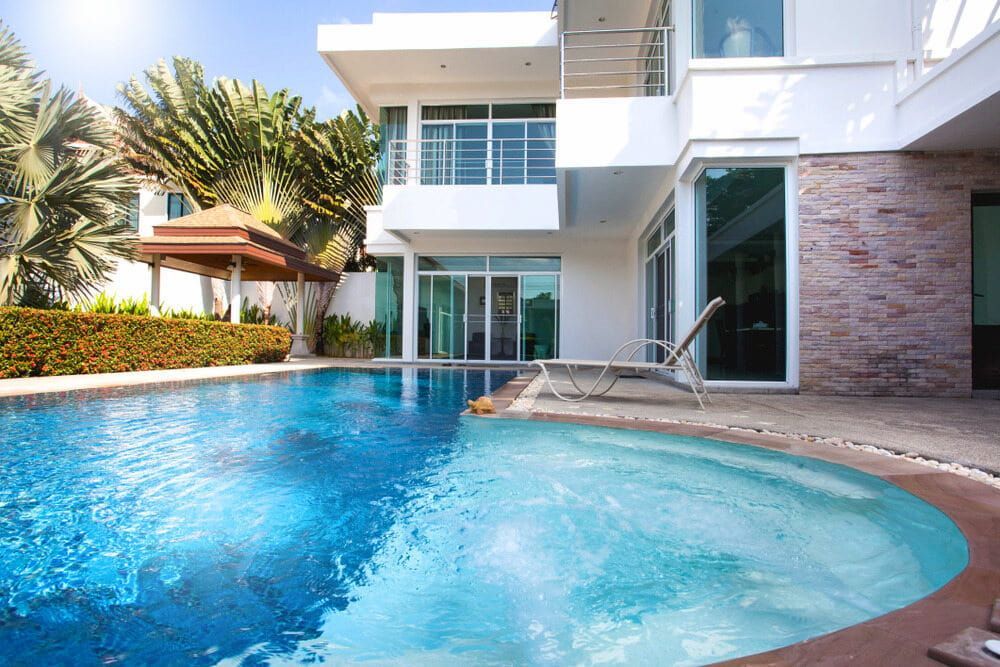 A Large House With A Swimming Pool In Front Of It — Solitary Island Pools in Coffs Harbour, NSW