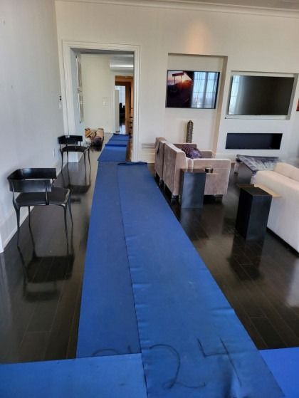 Blue runner rug laid down the length of a room, leading to a doorway.