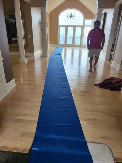 Blue runner rug laid in a hallway, man standing nearby. Light wood floor, arched doorway with light.