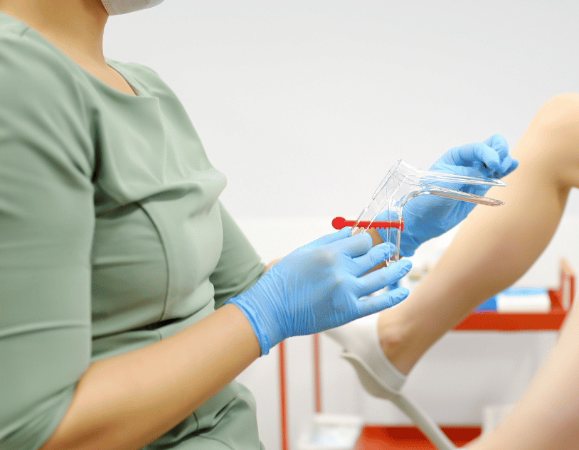 Medical professional preparing to use a speculum for a gynecological exam.
