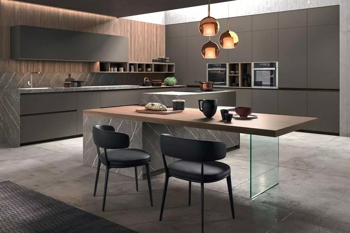 Cucina moderna grigia con isola, lampade a sospensione e due sedie nere in un elegante interno open space.