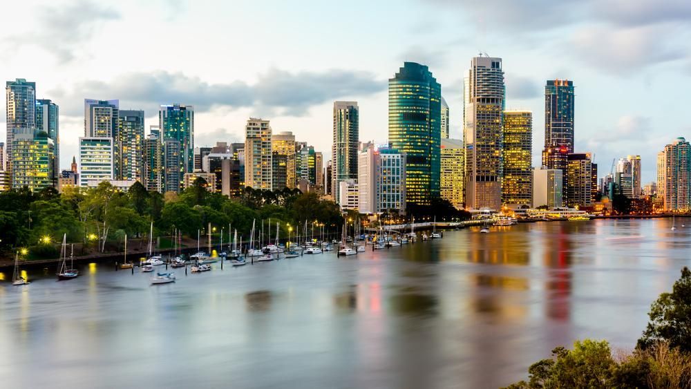 A City Skyline Over a Body of Water with Boats in The Water — Smillie Transport Pty Ltd in Brisbane, QLD