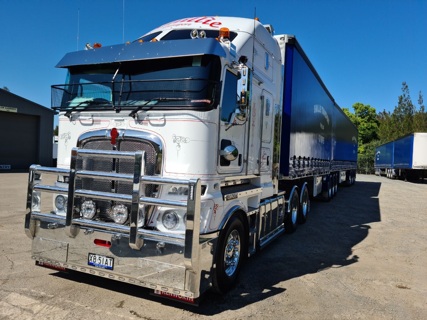A Red Truck Is Driving Down a Highway Next to A Bridge — Smillie Transport Pty Ltd in Toowoomba, QLD