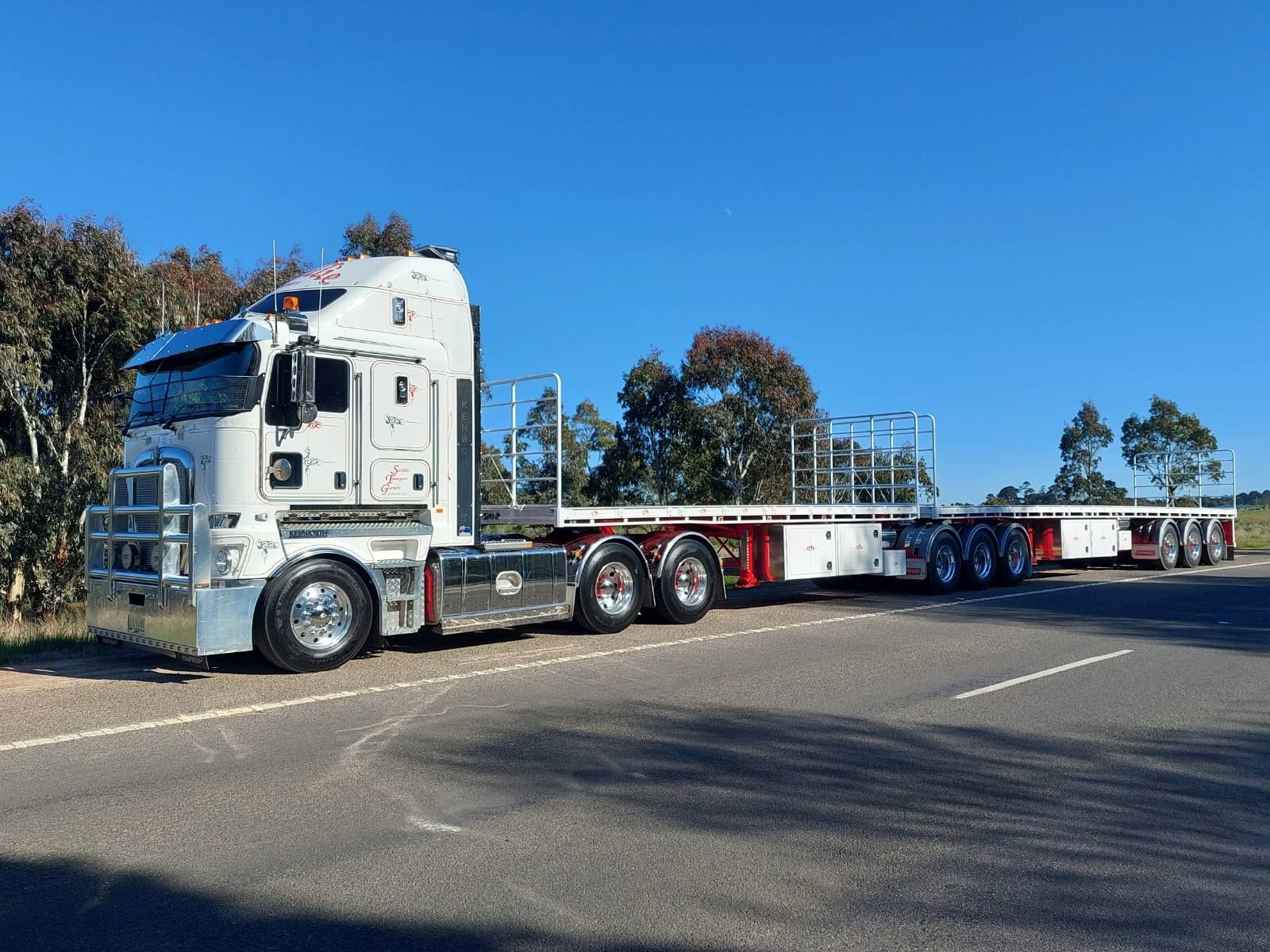 A Semi Truck Is Driving Down a Highway at Sunset — Smillie Transport Pty Ltd in Two Mile, QLD