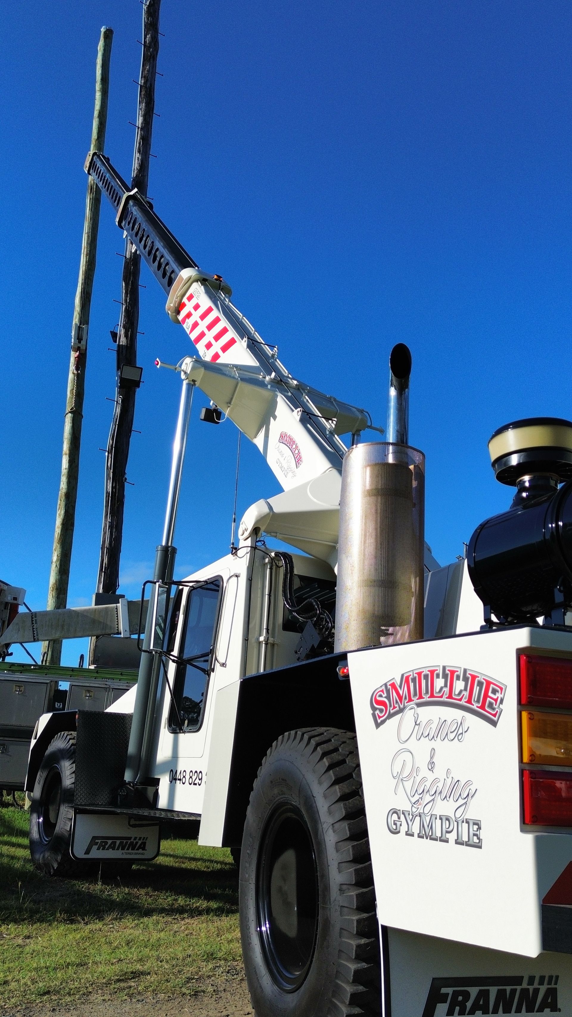 White Crane Truck With Raised Boom Beside Tall Utility Poles — Smillie Transport Pty Ltd in Two Mile, QLD