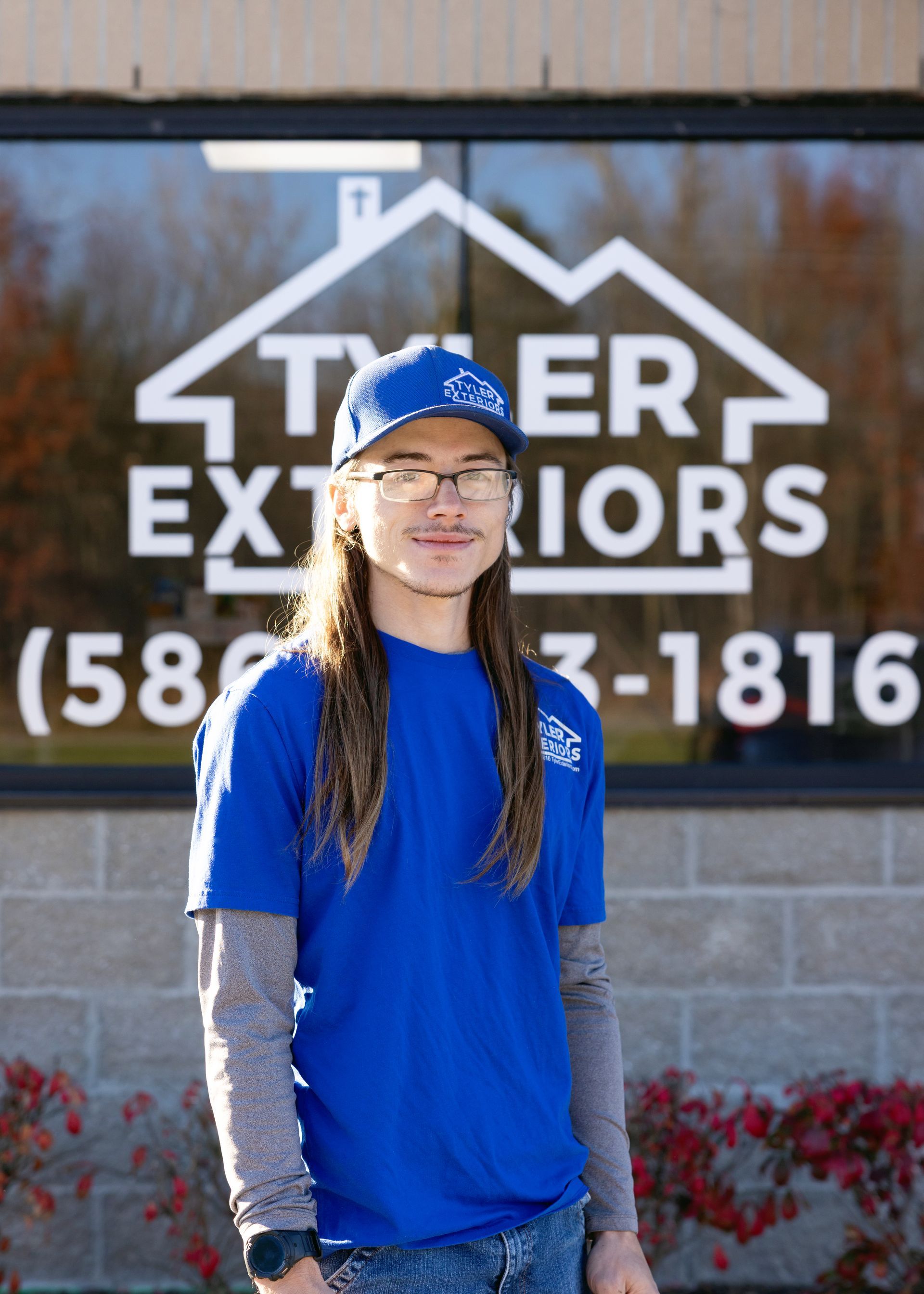Man in blue shirt and cap stands in front of 