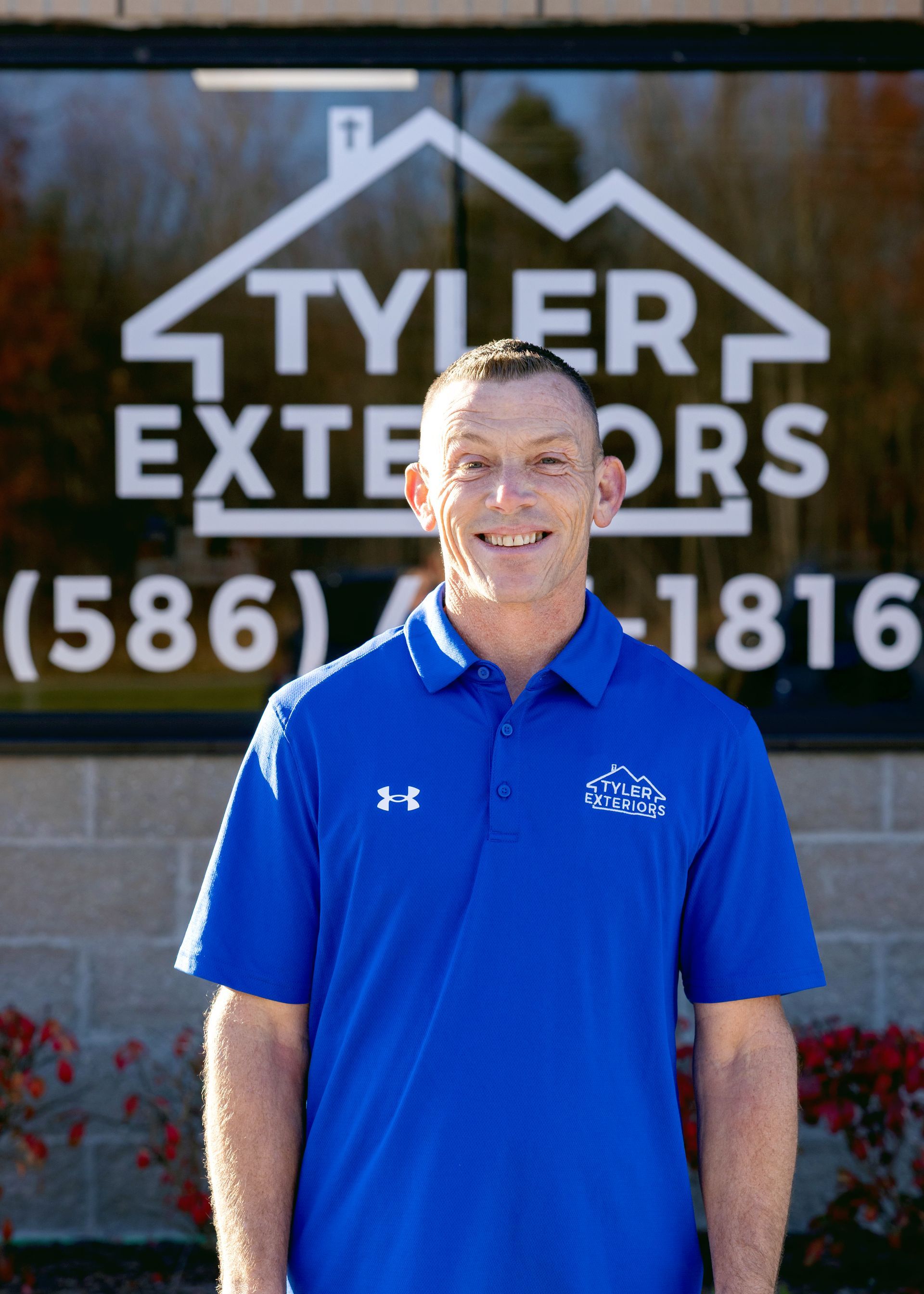 Man in blue shirt smiles in front of 