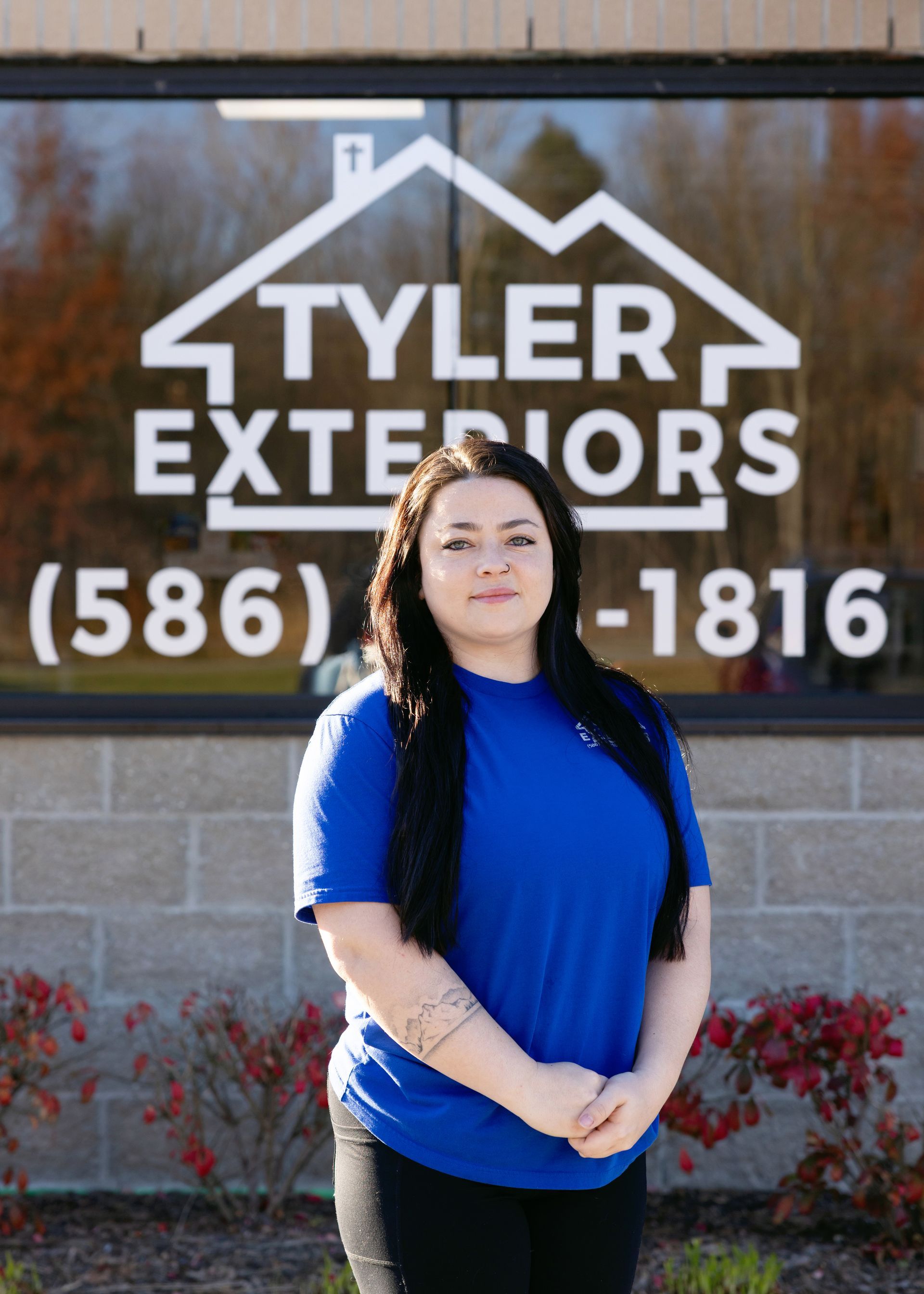 Woman in blue shirt stands in front of a 