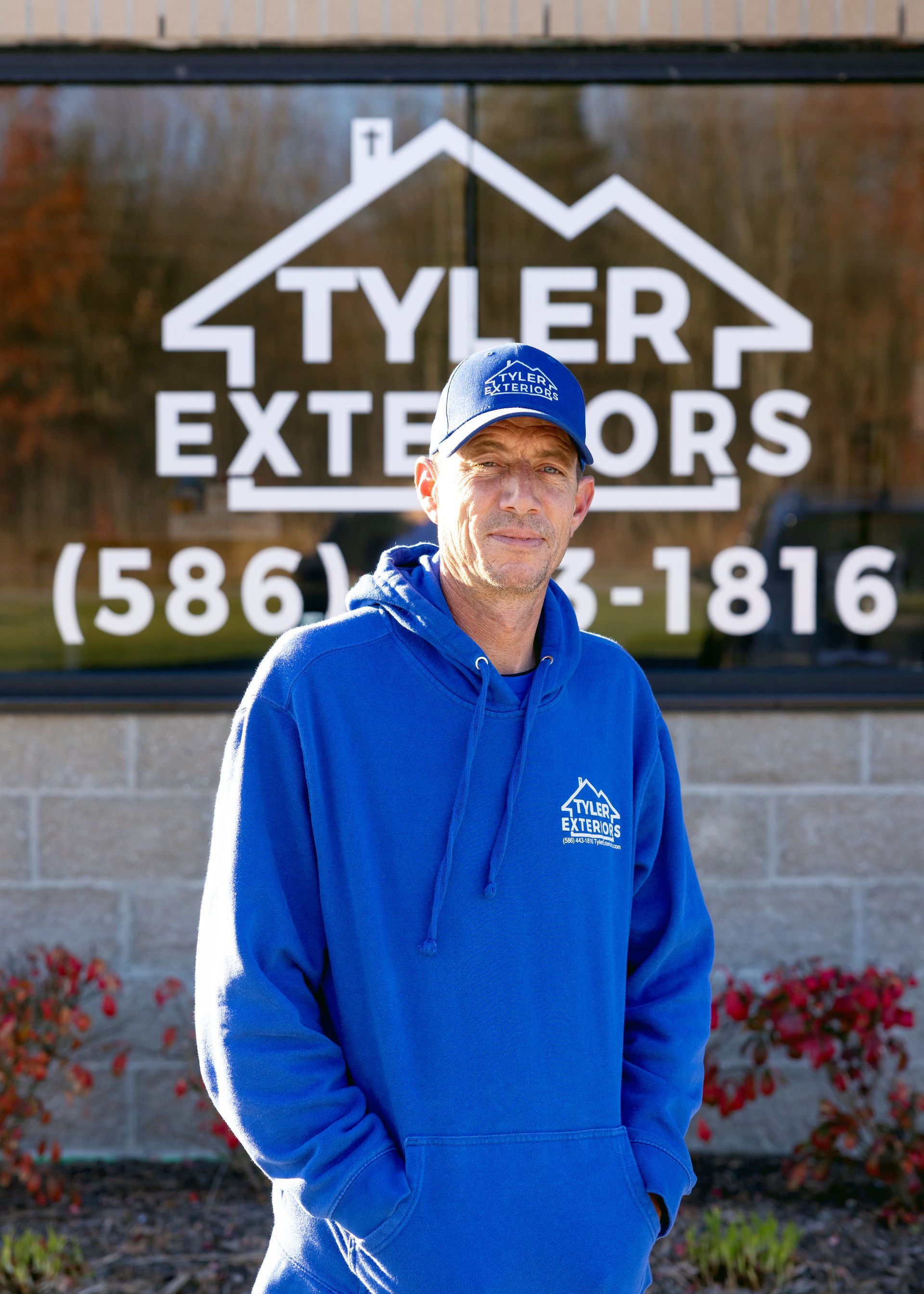 Man in blue sweatshirt stands in front of 