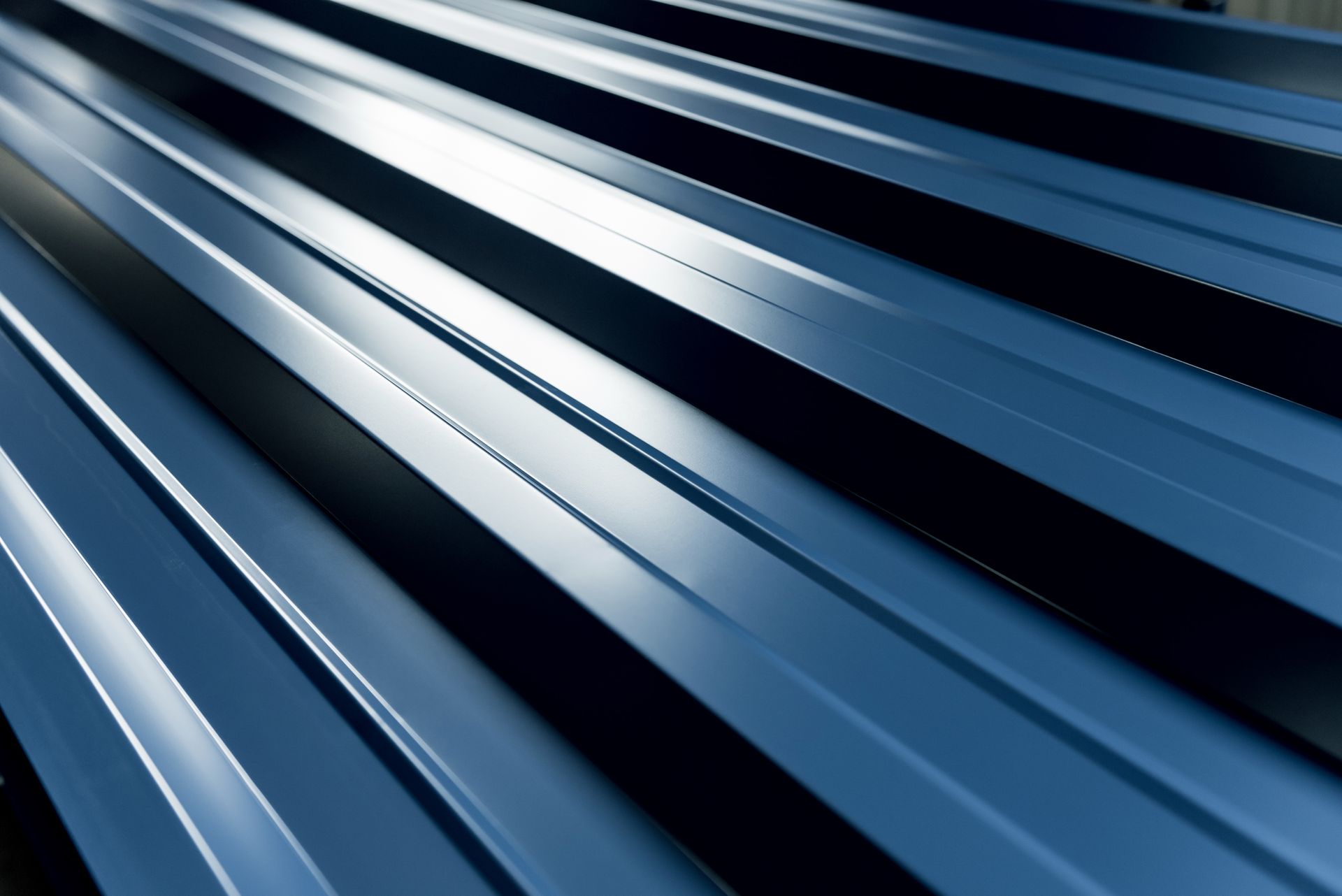 Close-up of a blue metal roof with parallel ridges reflecting light.