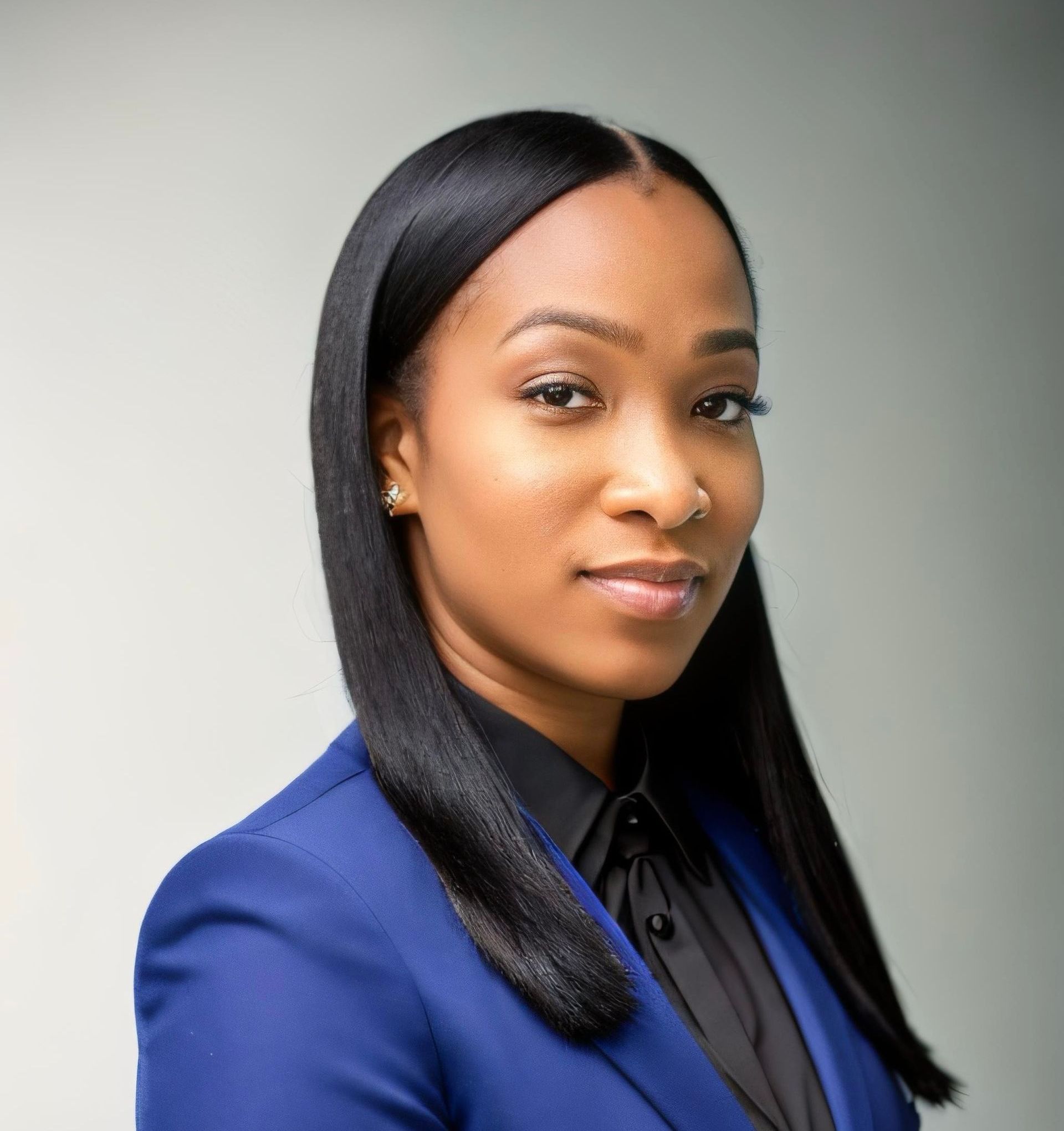 A woman in a blue jacket and black shirt is looking at the camera.