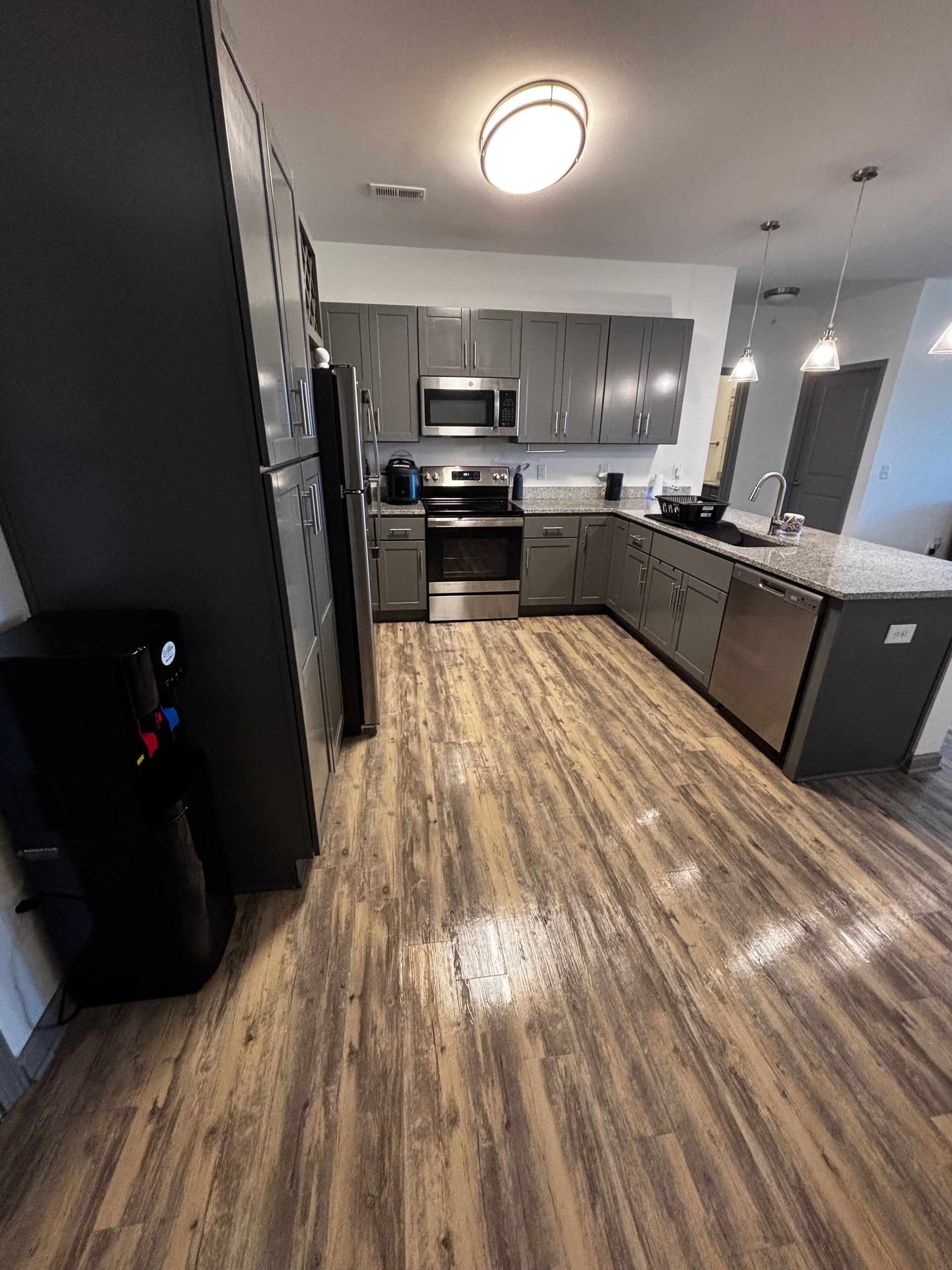A kitchen with stainless steel appliances and wooden floors.