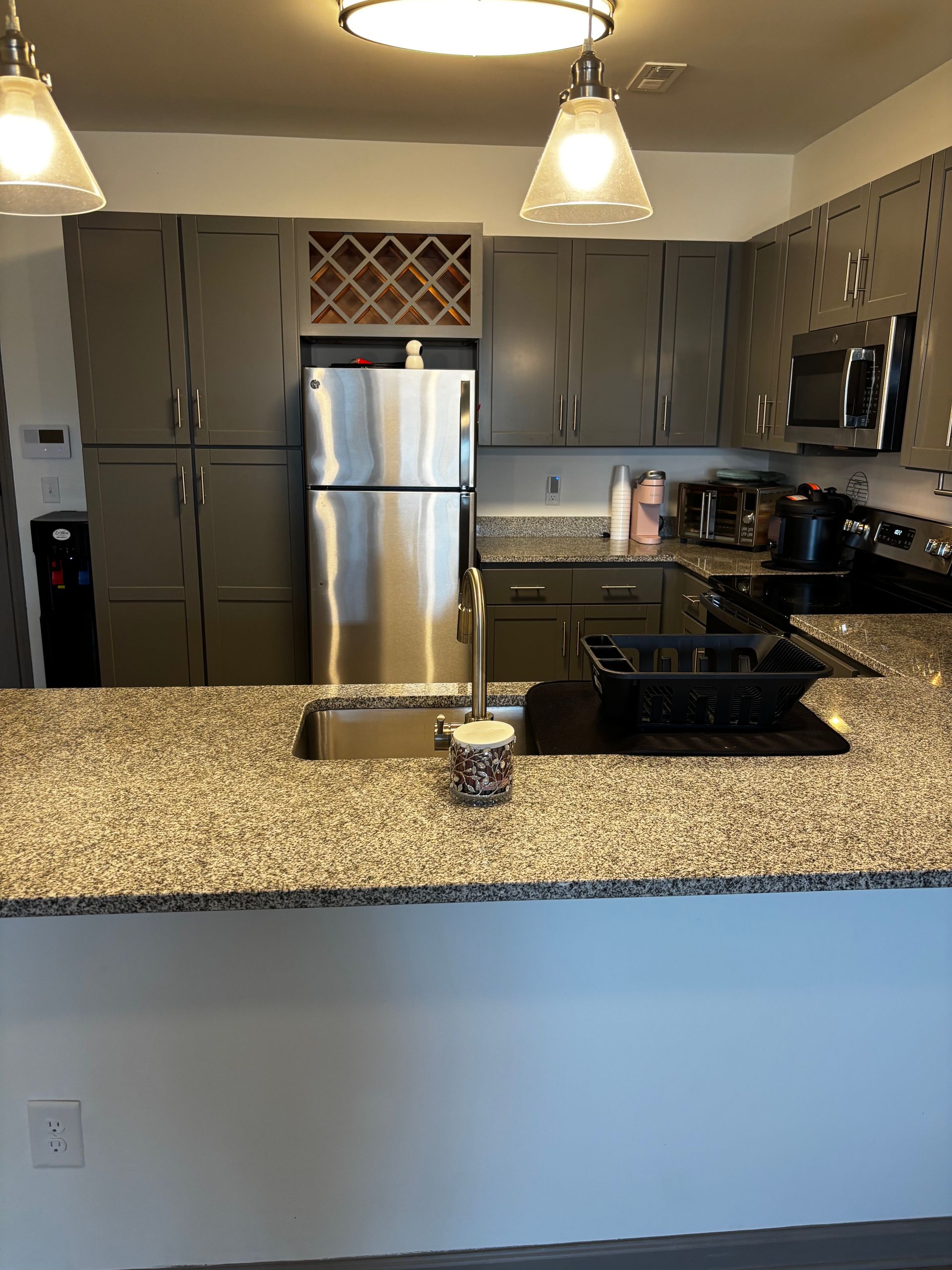 A kitchen with granite counter tops , stainless steel appliances , a refrigerator and a sink.