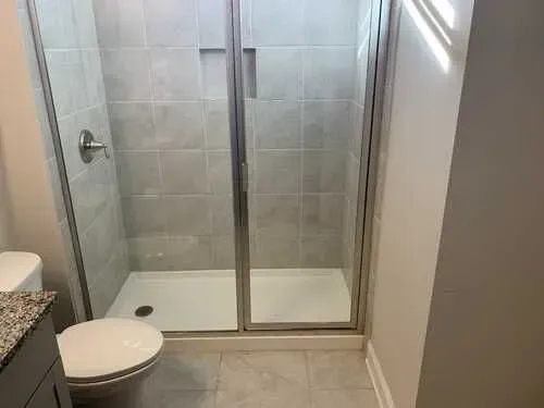 A bathroom with a toilet , shower , and vanity.