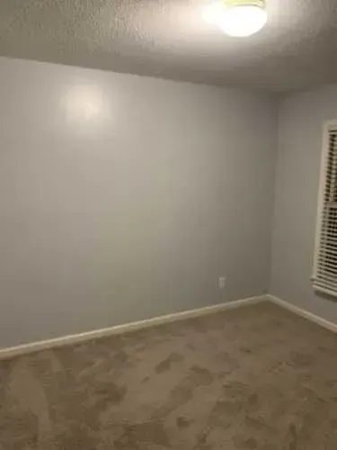 An empty bedroom with a window and blinds.