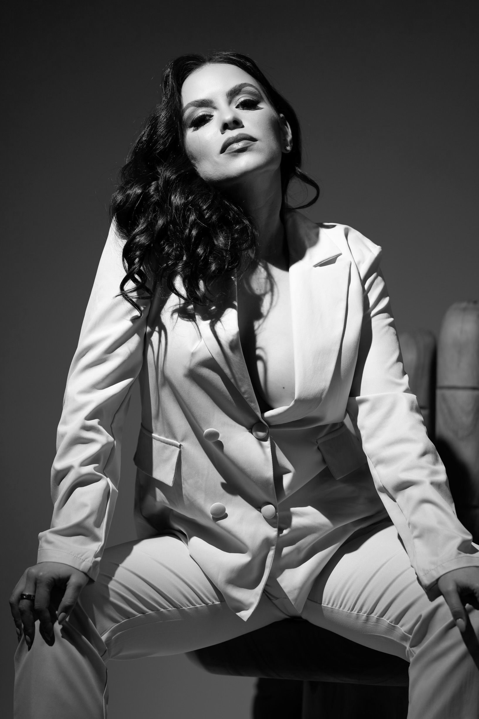 A black and white photo of a woman in a white suit