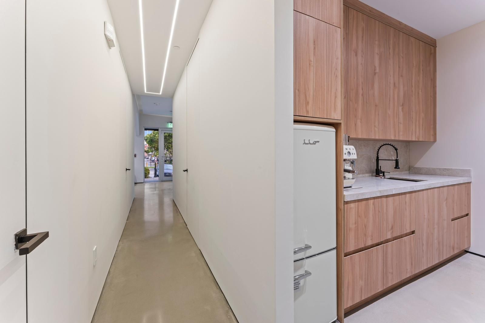 A long hallway next to a kitchen with wooden cabinets.
