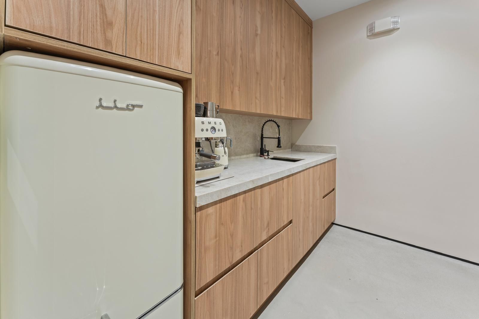 A kitchen with wooden cabinets , a refrigerator , a sink , and a coffee maker.