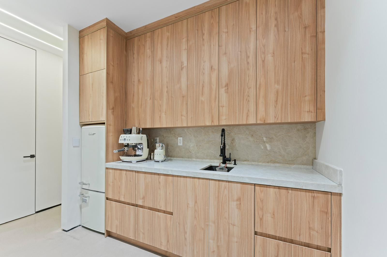 A kitchen with wooden cabinets , a sink , and a refrigerator.