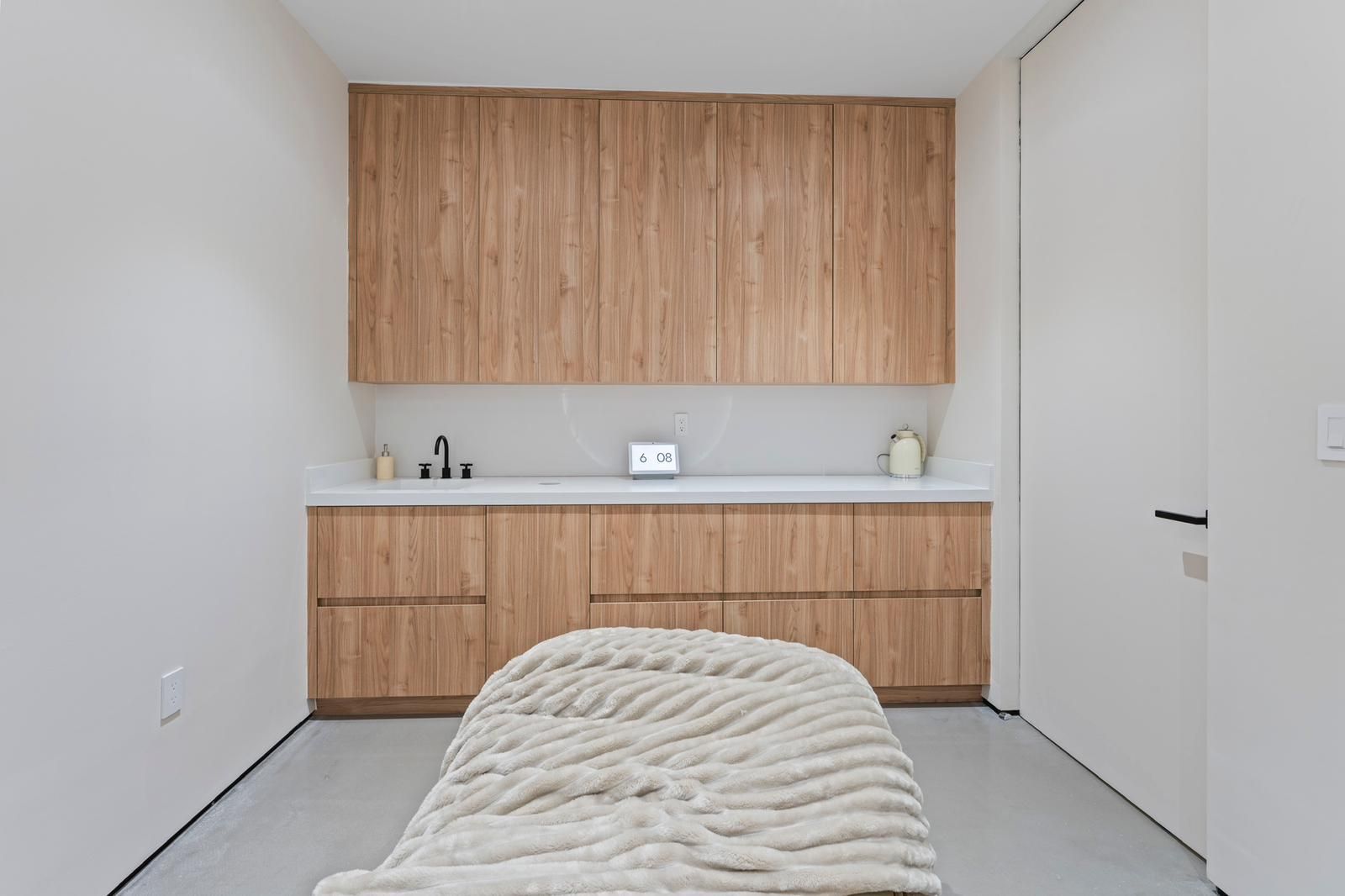 There is a bed in the middle of the room with wooden cabinets.
