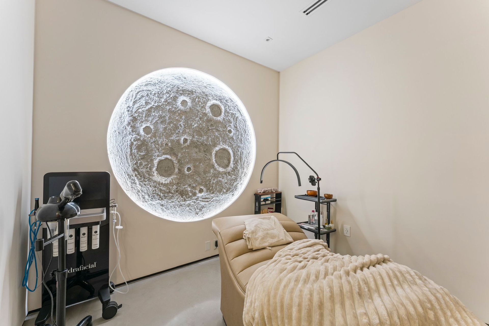 A room with a bed and a picture of the moon on the wall.