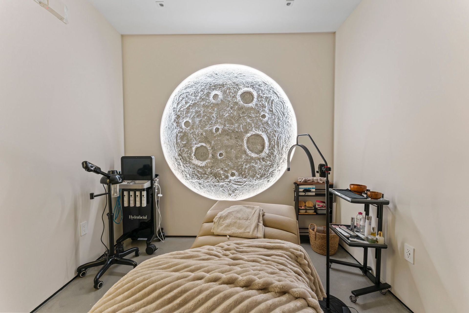 A room with a bed and a picture of the moon on the wall.