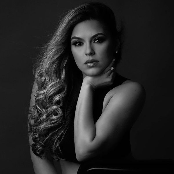 A black and white photo of a woman with her hand on her chin.