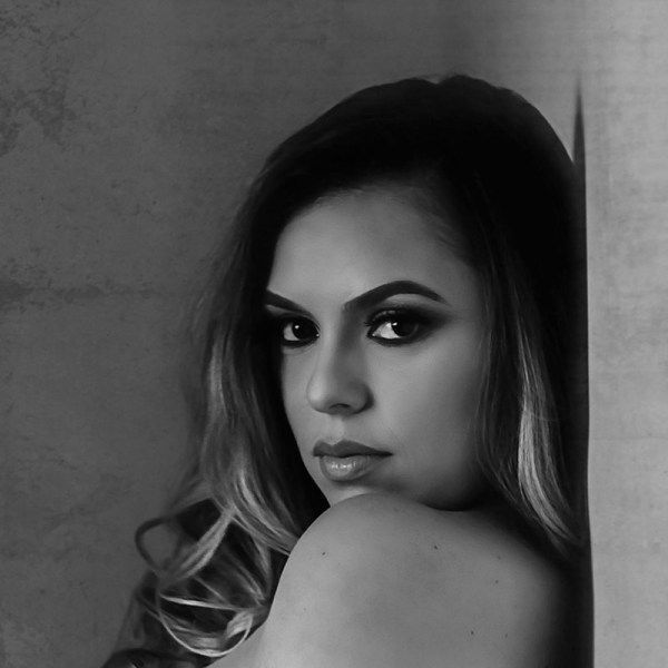 A black and white photo of a woman leaning against a wall.